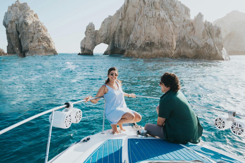 A couple enjoying a sunny day on a yacht with The Arch of Cabo San Lucas in the background.